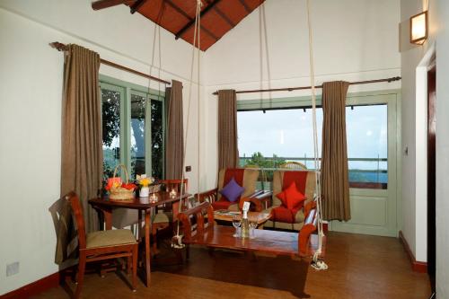 a living room with a table and chairs and a dining room at Blackberry Hills Munnar Nature Resort & Spa in Munnar