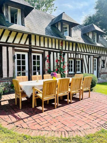 une table et des chaises devant une maison dans l'établissement Splendide longère de charme - Collection Idylliq, à Conteville