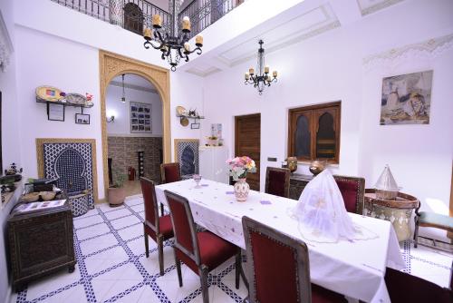 une salle à manger avec une table et des chaises blanches dans l'établissement RYAD RDATE LWALIDINE, à Marrakech