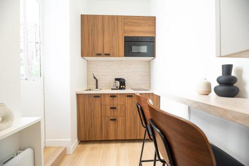 - une cuisine avec des armoires et des chaises en bois dans la chambre dans l'établissement Lovely & Romantic Suite near Bastille, à Paris