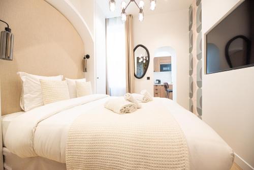 une chambre avec un grand lit blanc avec des serviettes dessus dans l'établissement Lovely & Romantic Suite near Bastille, à Paris