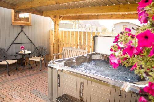 a hot tub on a patio with pink flowers at Lily in Rhayader