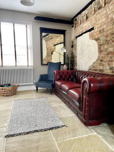 a living room with a leather couch and a blue chair at TudorRose Townhouse - A New Unique Town Centre Home in King's Lynn