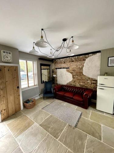 a living room with a red couch and a brick wall at TudorRose Townhouse - A New Unique Town Centre Home in King's Lynn