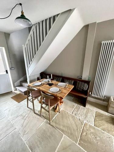 a dining room with a wooden table and a staircase at TudorRose Townhouse - A New Unique Town Centre Home in King's Lynn
