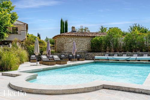 une piscine dans une cour avec des chaises et un bâtiment dans l'établissement Résidence Les Petitons, à Oppède
