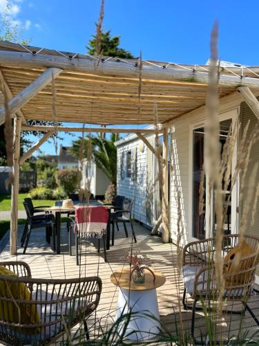 a patio with a wooden pergola and a table and chairs at Camping de la côte des légendes in Brignogan-Plages