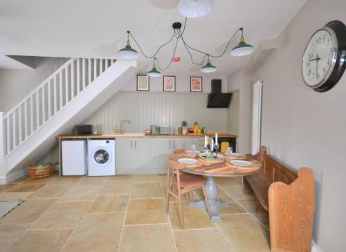 a kitchen with a table and a clock on the wall at St Nicholas Corner - A New Unique Town Centre Home in King's Lynn