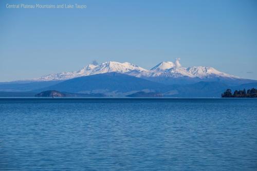 a view of a large body of water with snow covered mountains at Phoenix Thermal Resort - Taupo in Taupo