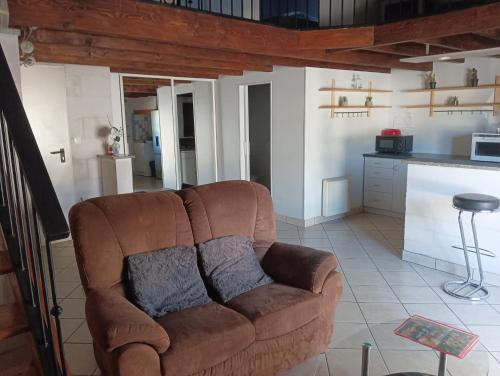 a brown couch in a living room with a kitchen at Le Petit Saint Jacques in Cognac