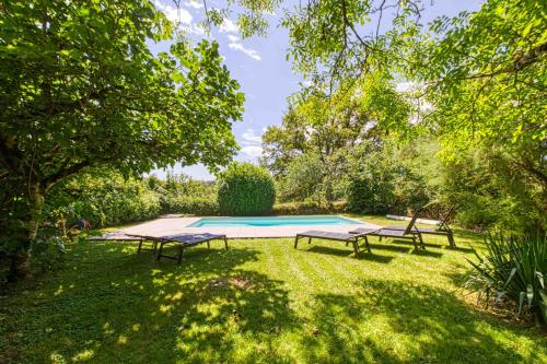 une cour avec deux bancs et une piscine dans l'établissement gite de bervic avec piscine, à Sainte-Croix