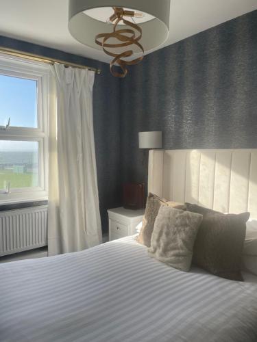 a bedroom with a bed with a ceiling fan and a window at The Lilly Restaurant With Rooms in Llandudno