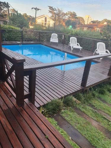 a wooden deck with a pool with chairs and a bench at Hosteria Nirvana in Villa Gesell