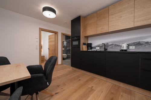 a kitchen with black cabinets and a table and chairs at A CASA Türkis in Sölden