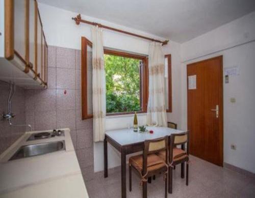 a kitchen with a table and a sink and a window at Apartments and Room Anita in Sumartin