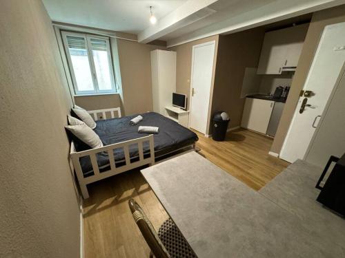 une petite chambre avec un lit et une cuisine dans l'établissement Appartement proche place de la réunion au calme, à Mulhouse