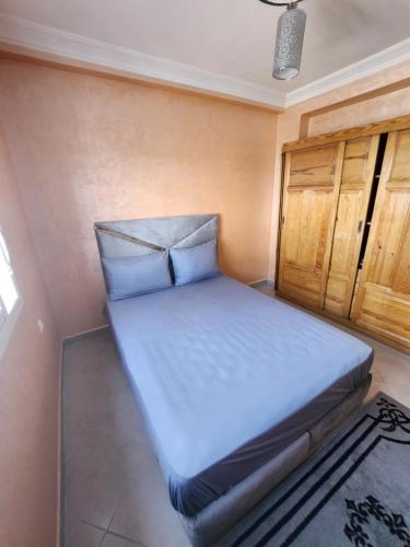 a small bedroom with a bed with white sheets at appart à louer proche de la mer in Agadir