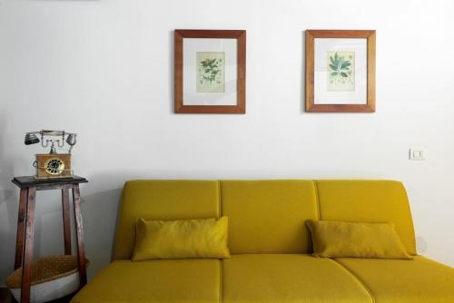 a yellow couch in a room with two pictures on the wall at Casa Matilde Chianti - Jeky Stay in Castelnuovo Berardenga