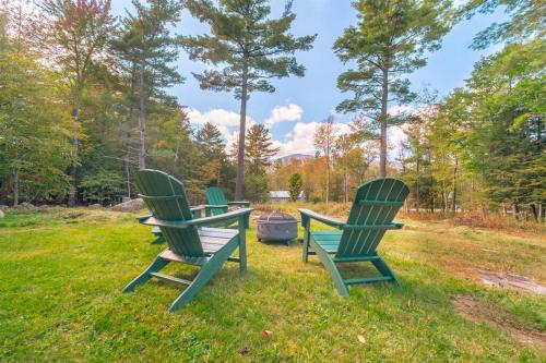 a group of three chairs sitting in the grass at ADK Whiteface Chalet with Hot Tub, Dog Friendly! in Wilmington