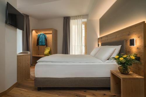 a bedroom with a large white bed and a television at Green Hotel Genzianella in Roncone