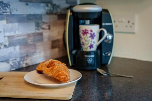 a croissant on a plate on a counter with a coffee maker at Peaceful 3-Bed Lodge ! Ideal for Families! in Warton