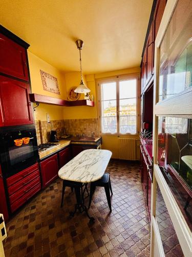 - une cuisine avec des placards rouges et une table dans l'établissement Le Repos du Marinier, à Gien