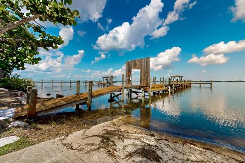 a wooden dock on the water with clouds in the sky at The Manatee Cove - Side B: Studio in Cocoa
