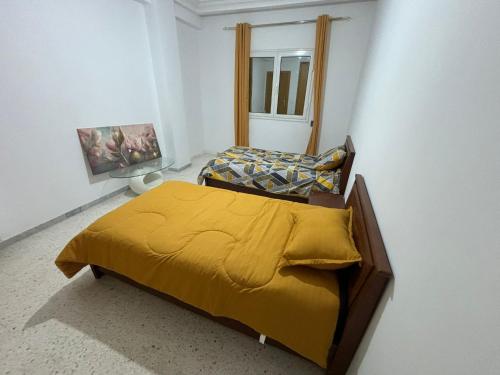a bedroom with a bed with a yellow blanket at Appart Meublé Cité ElWahat in El Aouina