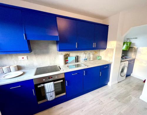 a blue kitchen with a sink and a dishwasher at Large 5 bed detached house near Stansted Airport with Parking for 2 vehicles! Stansted Stays in Stansted Mountfitchet