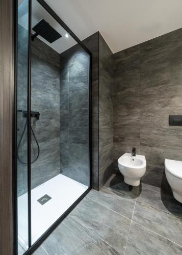 a bathroom with a shower and a toilet and a sink at Green Hotel Genzianella in Roncone
