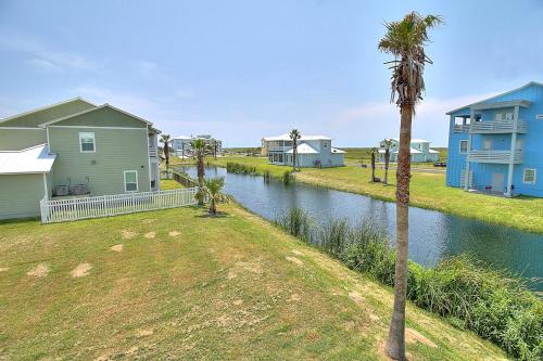 a canal with houses and a palm tree next to a river at Cute As Shell IPE125 in Padre Island