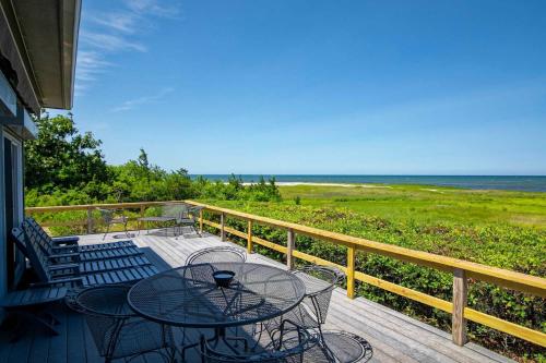 a balcony with a table and chairs and the ocean at Waterfront on Cape Cod Bay in Orleans