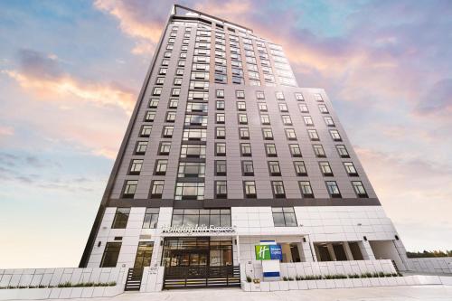 a tall white building with a sky in the background at Holiday Inn Express Long Island City E - New York by IHG in Queens
