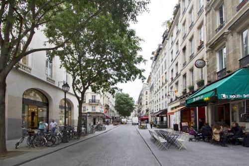 une rue de la ville avec des bâtiments et des personnes assises sur des chaises dans l'établissement Elegant Retreat by Le Marais, à Paris