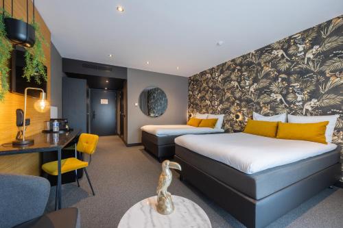 a hotel room with two beds and a desk at Van Der Valk Hotel Brugge Oostkamp in Oostkamp