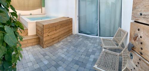 La salle de bains est pourvue d'un bain à remous et de 2 chaises. dans l'établissement xenónas appartement avec petite piscine privée, au Grau-dʼAgde