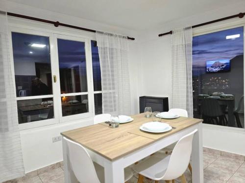 a white dining room with a table and chairs at Departamentos aćawaia in Ushuaia