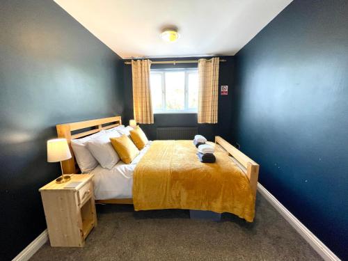 a bedroom with a bed with a yellow blanket and a window at Large 5 bed detached house near Stansted Airport with Parking for 2 vehicles! Stansted Stays in Stansted Mountfitchet