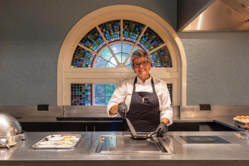 a woman standing in a kitchen preparing food at Van Der Valk Hotel Brugge Oostkamp in Oostkamp