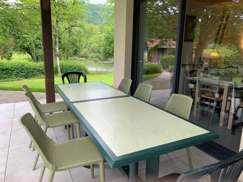 une table et des chaises vertes sur la terrasse dans l'établissement Gite du Lison 2 chambres au calme en Franche Comte riviere, à Nans-sous-Sainte-Anne