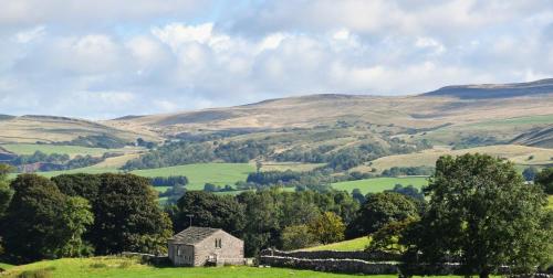 an old house on a hill with hills in the background at Stay Lambing Live in Kirkby Stephen