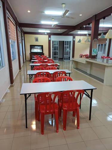 a row of tables and red chairs in a cafeteria at Lemuni Retreat & Training Centre - Kerling, Selangor in Kerling