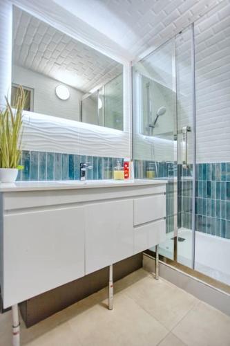 une salle de bain avec un lavabo blanc et une douche dans l'établissement Le Nid Parisien Triplex Cosy et Chaleureux, à Paris