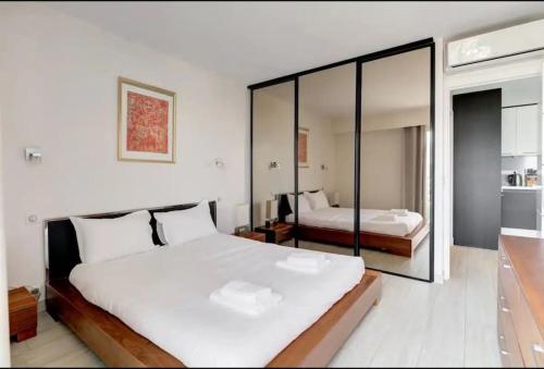une chambre avec deux lits et un grand miroir dans l'établissement Cannes Palm Beach - 2 chambres Vue mer, à Cannes