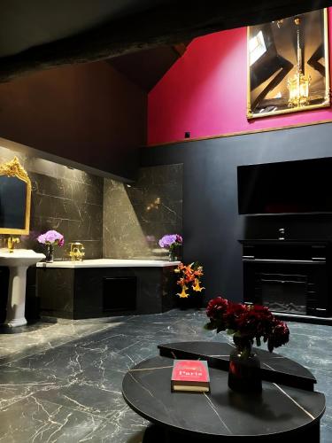 La salle de bains est pourvue d'une table et d'un vase de fleurs. dans l'établissement L'Orchidarium, maison élégante et romantique à Flagy, à Flagy