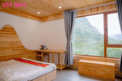 a bedroom with a bed and a desk and a window at Meo Vac Valley in Mèo Vạc