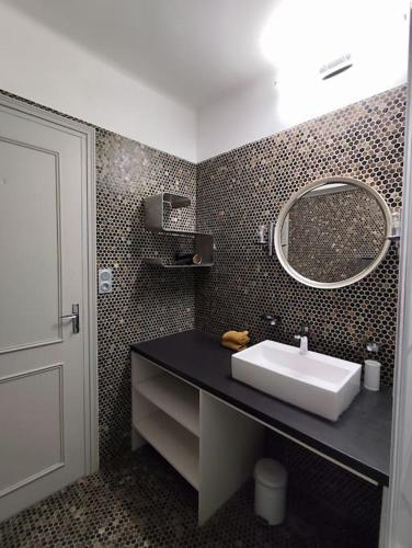 une salle de bain avec un lavabo et un miroir dans l'établissement Le Balcon des Pyrénées, à Lourdes