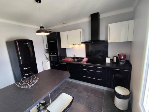 une cuisine avec des armoires en noir et blanc et un comptoir dans l'établissement Le Balcon des Pyrénées, à Lourdes