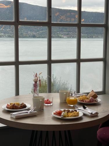 a table with plates of food on it with a window at Le Palace De Menthon in Menthon-Saint-Bernard