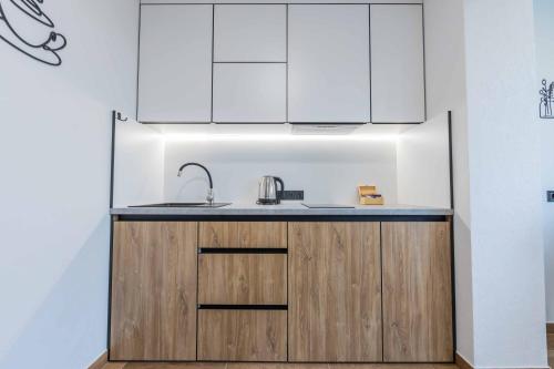 a kitchen with white cabinets and a sink at CityApartments Kyiv Heroiv Dnipra in Kyiv